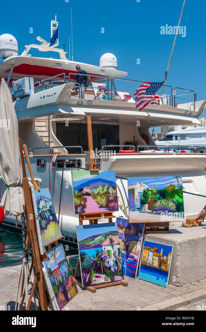 Paintings and yacht at the promenade Quai Jean Jaures, Saint-Tropez, Var, Provence-Alpes-Cote d`Azur, France, Europe Stock Photo